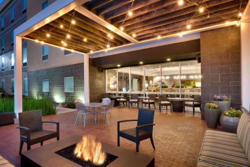 eine Terrasse mit einer Feuerstelle sowie Tischen und Stühlen in der Unterkunft Home2 Suites by Hilton Houston Katy in Katy
