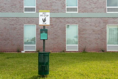 a trash can in the grass in front of a brick building at Home2 Suites by Hilton Houston Katy in Katy