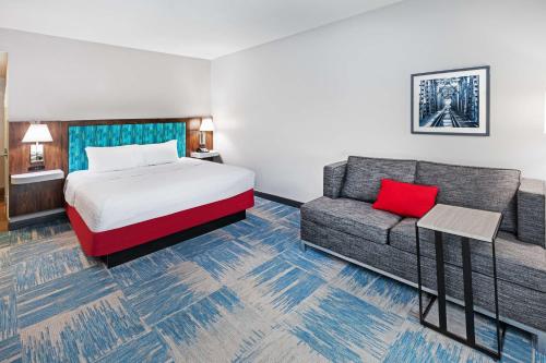 Hampton Inn and Suites Houston Central في هيوستن: غرفه فندقيه بسرير واريكه