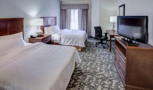 a hotel room with two beds and a flat screen tv at Homewood Suites by Hilton Houston Stafford Sugar Land in Stafford