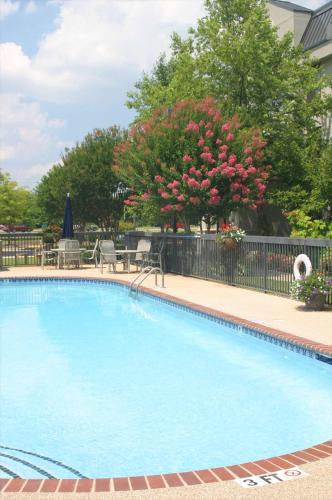 a large blue swimming pool with chairs and a fence at Hampton Inn Huntsville-Madison in Madison