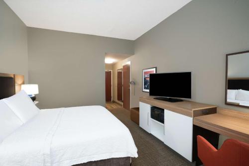 a hotel room with a bed and a flat screen tv at Hampton Inn Huntsville-Madison in Madison