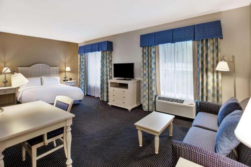 a hotel room with a bed and a living room at Hampton Inn & Suites - Cape Cod / West Yarmouth in West Yarmouth