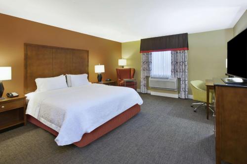 Habitación de hotel con cama, escritorio y TV. en Hampton Inn & Suites Wichita-Northeast, en Wichita