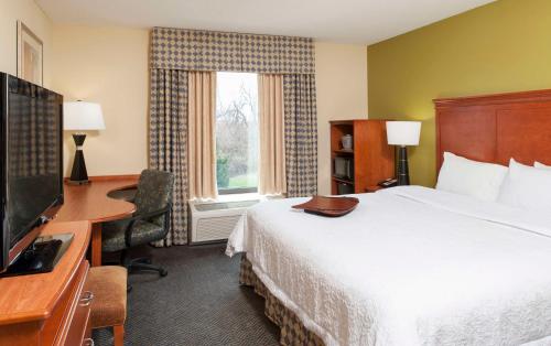 Una habitación de hotel con una cama, un escritorio y un televisor. en Hampton Inn Jacksonville, en Jacksonville