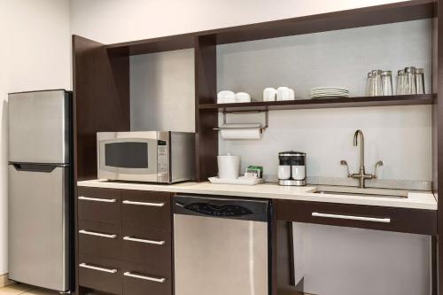 a kitchen with a refrigerator and a microwave at Home2 Suites Long Island City/Manhattan View in Queens