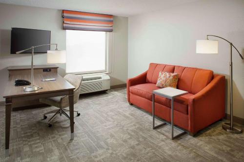 a living room with an orange couch and a desk at Hampton Inn by Hilton Garden City Long Island in Garden City