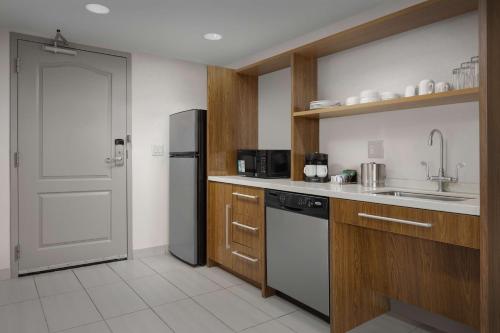 a kitchen with a refrigerator and a sink at Home2 Suites by Hilton Jacksonville, NC in Jacksonville