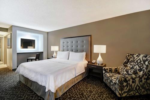 a hotel room with a bed and a chair at Homewood Suites by Hilton Edgewater-NYC Area in Edgewater