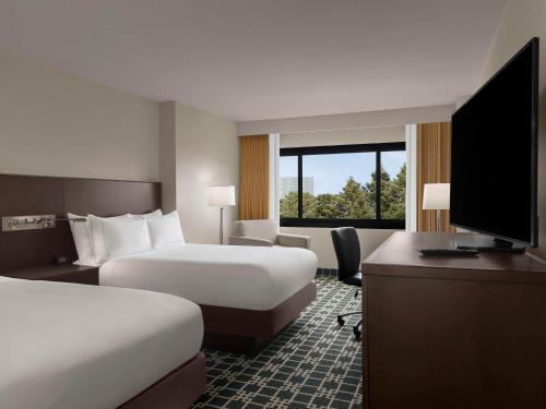 a hotel room with two beds and a desk and a television at DoubleTree by Hilton Fort Lee/George Washington Bridge in Fort Lee
