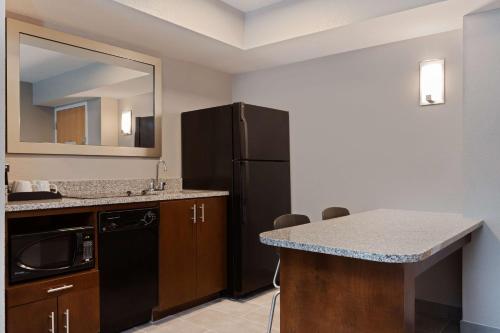 a kitchen with a black refrigerator and a counter at Hampton Inn & Suites Fort Myers Beach/Sanibel Gateway in Fort Myers Beach