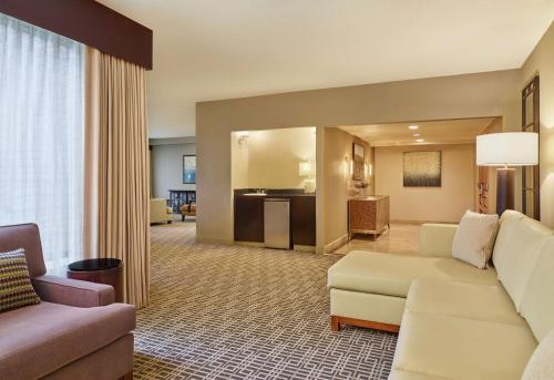 a living room with a white couch and a living room with a kitchen at DoubleTree by Hilton Houston Intercontinental Airport in Houston