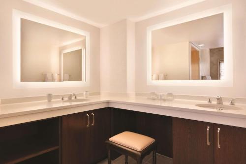 a bathroom with two sinks and two mirrors at Embassy Suites Greenville Golf Resort & Conference Center in Greenville