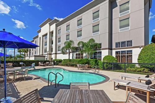 a pool with tables and chairs and a building at Hampton Inn & Suites Houston-Bush Intercontinental Airport in Houston