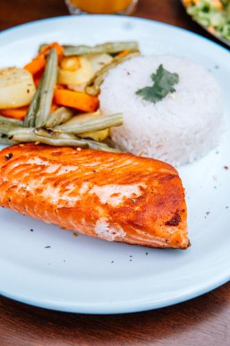 a white plate with a piece of fish and rice at Espaço Villa Verde in Ibiúna