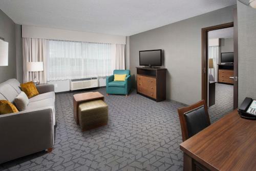 a hotel room with a couch and a television at Homewood Suites by Hilton Gaithersburg/Washington, DC North in Gaithersburg