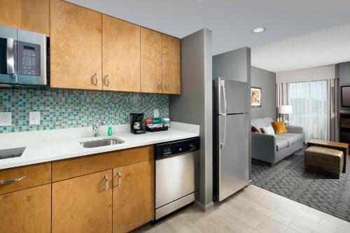 a kitchen with stainless steel appliances and a living room at Homewood Suites by Hilton Gaithersburg/Washington, DC North in Gaithersburg