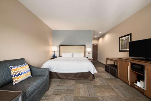a bedroom with a bed and a couch and a tv at Hampton Inn & Suites - Lavonia, GA in Lavonia