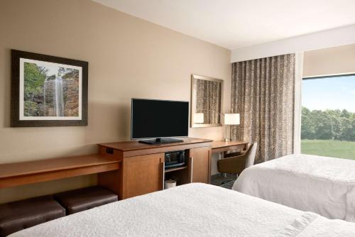 a hotel room with two beds and a desk with a television at Hampton Inn & Suites - Lavonia, GA in Lavonia