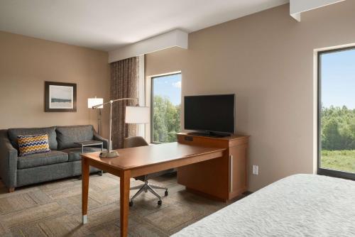 a hotel room with a desk with a television and a couch at Hampton Inn & Suites - Lavonia, GA in Lavonia