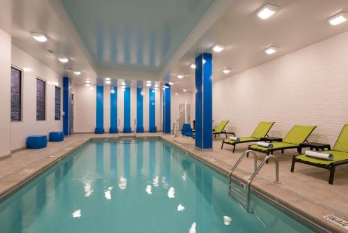 a swimming pool with green chairs and chairs in a building at Homewood Suites by Hilton Grand Rapids Downtown in Grand Rapids