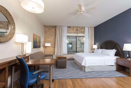 Habitación de hotel con cama, escritorio y mesa. en Homewood Suites by Hilton Grand Rapids Downtown, en Grand Rapids
