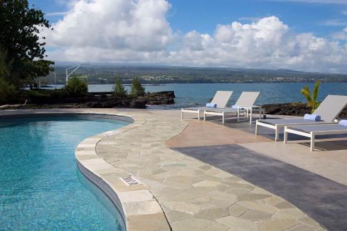 a swimming pool with lounge chairs next to the water at Grand Naniloa Hotel, a Doubletree by Hilton in Hilo
