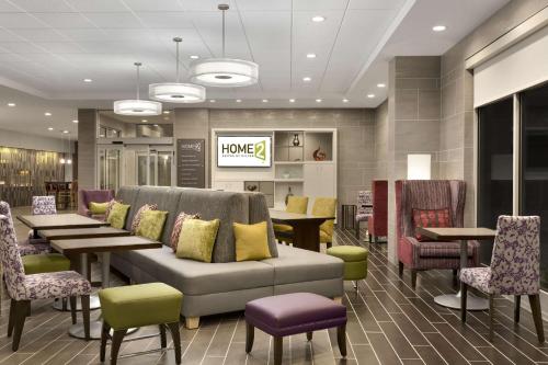 vestíbulo con sofá, mesas y sillas en Home2 Suites by Hilton Greenville Downtown en Greenville