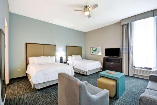 a hotel room with two beds and a couch at Homewood Suites By Hilton Galveston in Galveston
