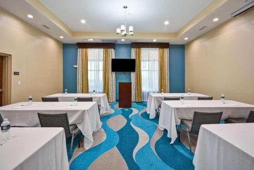 a conference room with white tables and chairs and a screen at Homewood Suites By Hilton Galveston in Galveston
