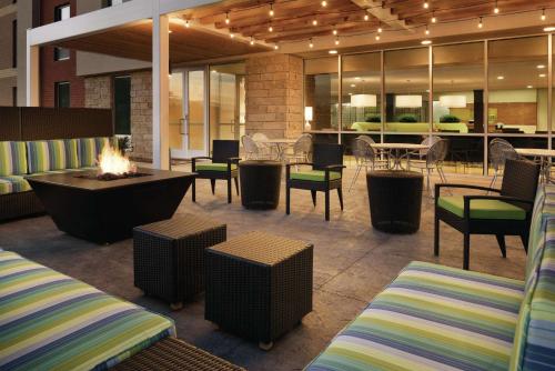 a patio with chairs and tables and a fire place at Home2 Suites By Hilton Iowa City Coralville in Coralville