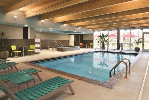 a pool in a hotel with chairs and a table at Home2 Suites By Hilton Iowa City Coralville in Coralville