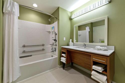 a bathroom with a sink and a tub and a mirror at Home2 Suites by Hilton Gulfport I-10 in Gulfport