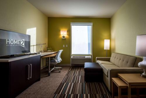 a living room with a couch and a desk with a computer at Home2 Suites by Hilton Gulfport I-10 in Gulfport