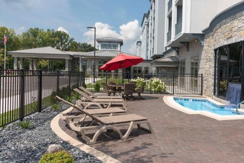 a group of chairs and an umbrella next to a pool at Hilton Garden Inn Grand Rapids East in Grand Rapids