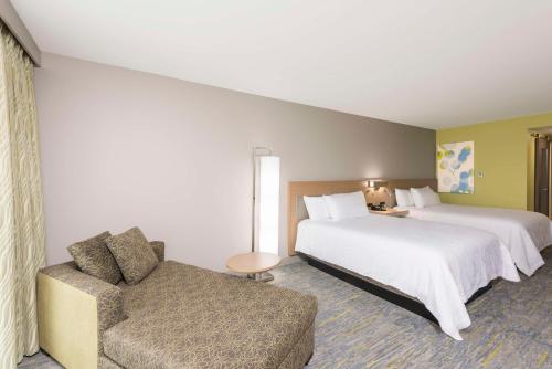 Habitación de hotel con 2 camas y sofá en Hilton Garden Inn Grand Rapids East, en Grand Rapids