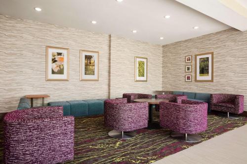 a waiting room with purple chairs and a table at Hilton Garden Inn Houston-Baytown in Baytown