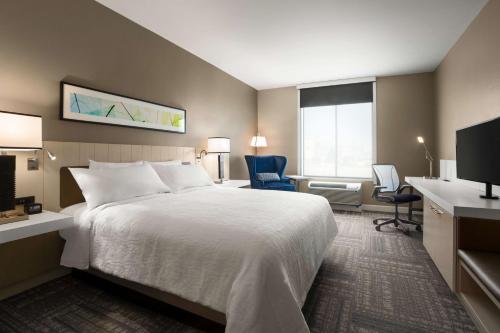 ein Hotelzimmer mit einem Bett und zwei Stühlen in der Unterkunft Hilton Garden Inn Houston-Baytown in Baytown