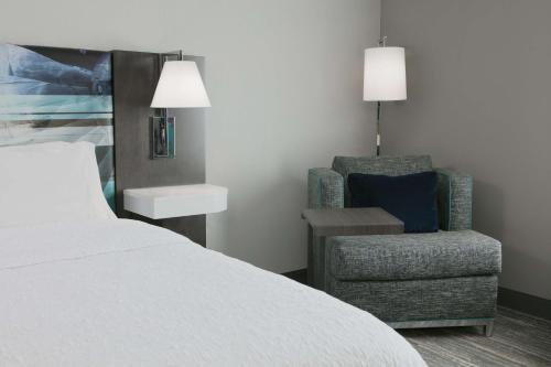 a hotel room with a bed and a chair at Hampton Inn By Hilton Wichita Northwest in Wichita