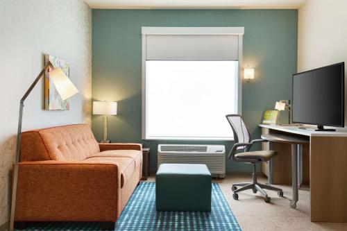 a living room with a couch and a desk with a computer at Home2 Suites By Hilton Frederick in Frederick