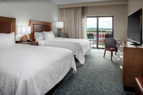 a hotel room with two beds and a balcony at Embassy Suites By Hilton Grand Rapids Downtown in Grand Rapids