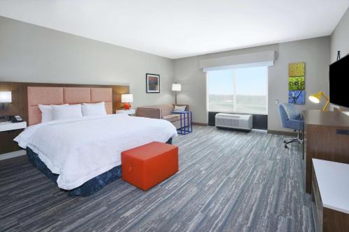 Pokój hotelowy z dużym łóżkiem i telewizorem w obiekcie Hampton Inn & Suites Grandville Grand Rapids South w mieście Grandville