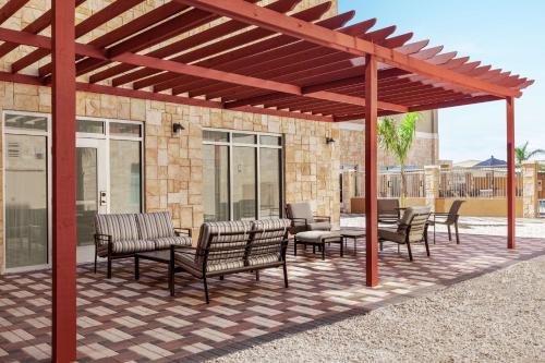 a wooden pergola with chairs and tables on a patio at Homewood Suites By Hilton Harlingen in Harlingen