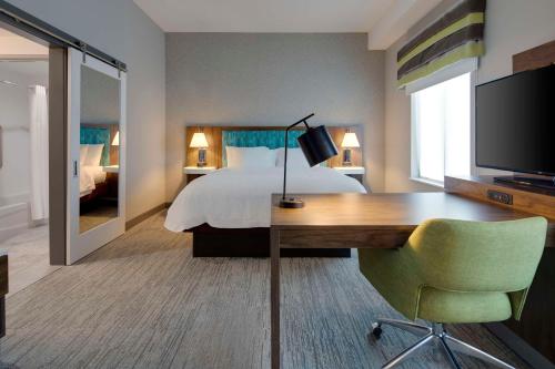 a hotel room with a bed and a desk with a television at Hampton Inn & Suites D'Iberville Biloxi in Biloxi