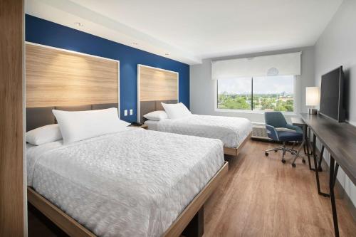 a hotel room with two beds and a desk and a window at Tru By Hilton Ft Lauderdale Airport in Dania Beach