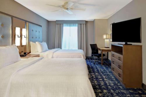 a hotel room with two beds and a flat screen tv at Homewood Suites By Hilton Orange New Haven in Orange