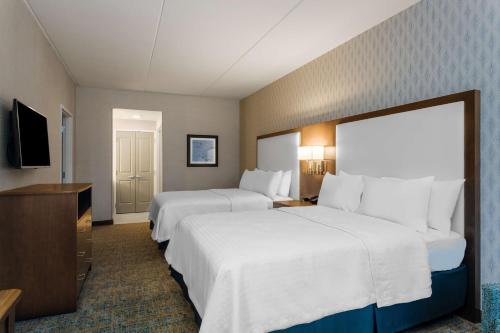 a hotel room with two beds and a television at Homewood Suites By Hilton Reston, VA in Reston