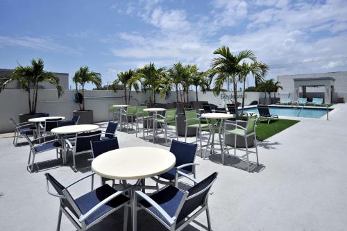 eine Terrasse mit Tischen und Stühlen und einem Pool in der Unterkunft Hotel Dello Ft Lauderdale Airport, Tapestry Collection by Hilton in Dania Beach