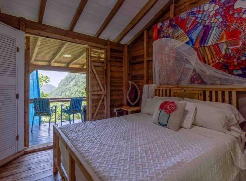 a bedroom with a bed and a painting on the wall at Sizo Treehouse Cottage in Roseau