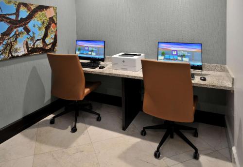 a desk with two computer monitors and two chairs at Hotel Dello Ft Lauderdale Airport, Tapestry Collection by Hilton in Dania Beach